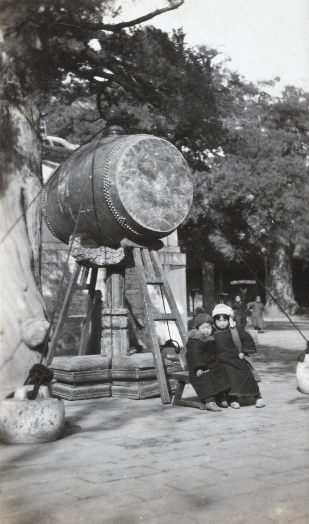 Children beside a large drum on a stand at a temple