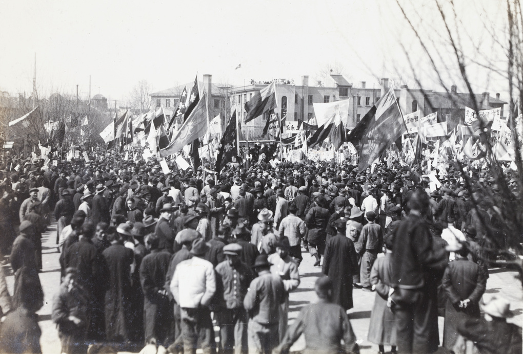 A large crowd around a group with flags and banners, Shanghai