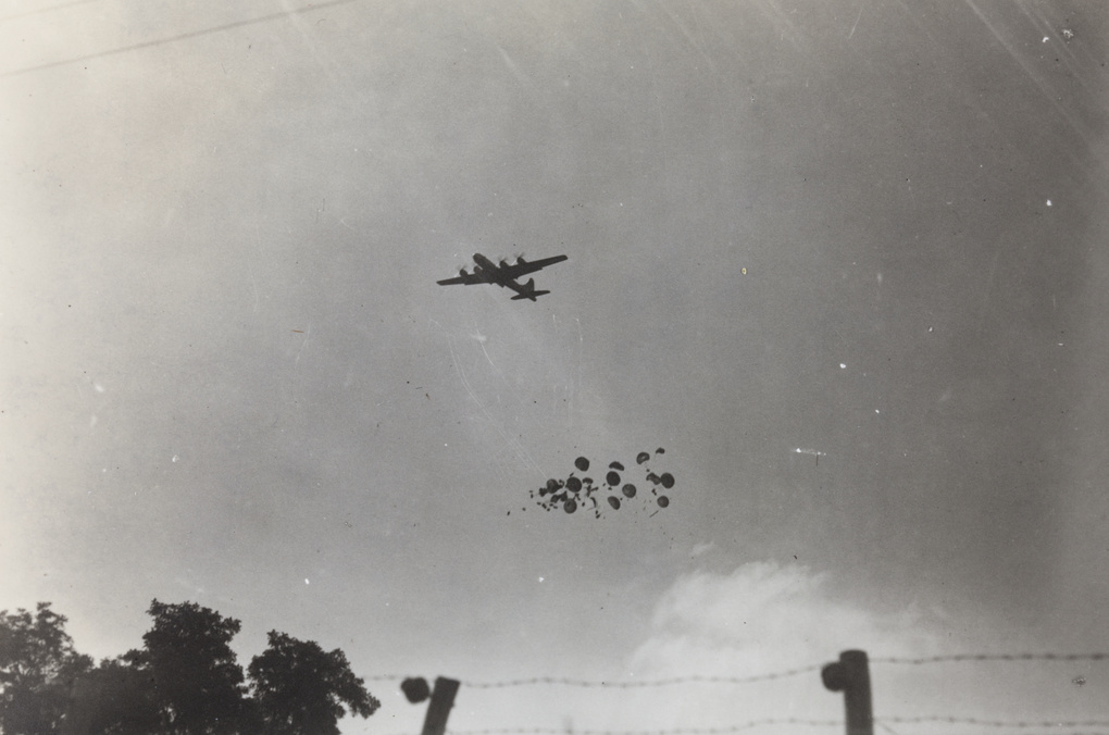 An American plane dropping food and clothing in ‘barrel bombs’ on Weixian (Weihsien) Civilian Assembly Centre, Weifang