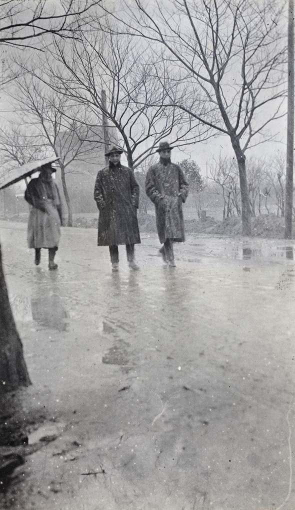 Man with a parasol, and Charles and Bill Hutchinson walking along Tongshan Road in sleet, Hongkou, Shanghai, February 1919