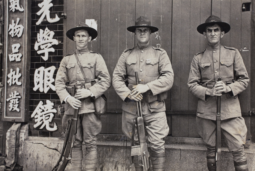 Three American Company Shanghai Volunteer Corps men standing guard with rifles, Shanghai, 1925