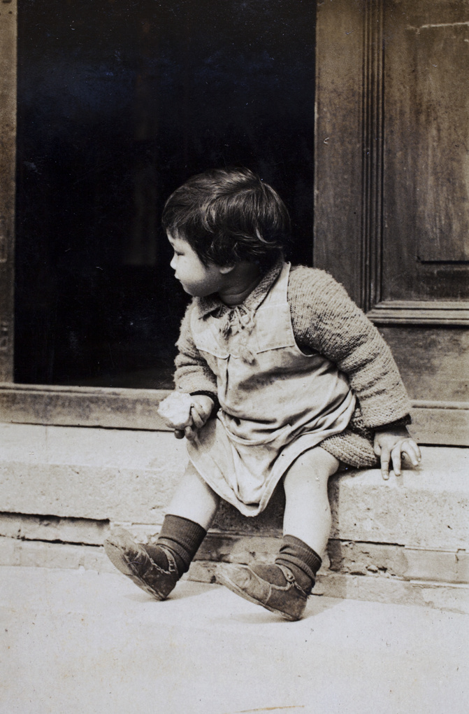 Gladys Hutchinson sitting on the verandah steps, holding a half-eaten fruit, 35 Tongshan Road, Hongkou, Shanghai 