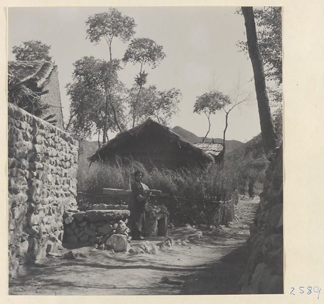 Woman on a village street with houses and stone walls in Lost Tribe country