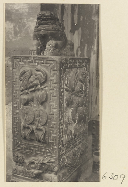 Carved door stone with bat and coin motifs and animal finial