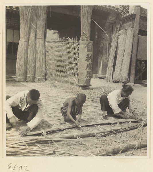 Man, boy, and woman weaving a mat at a mat-making shop