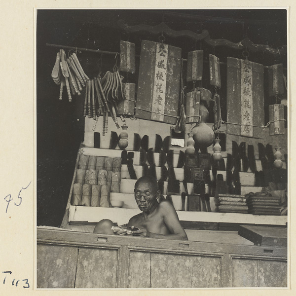 Shop front showing shopkeeper, wooden combs and household goods, and shop signs in Tai'an