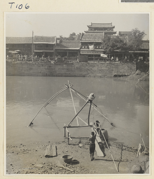 Man raising a fishing net attached to a wooden framework on the river at Tai'an