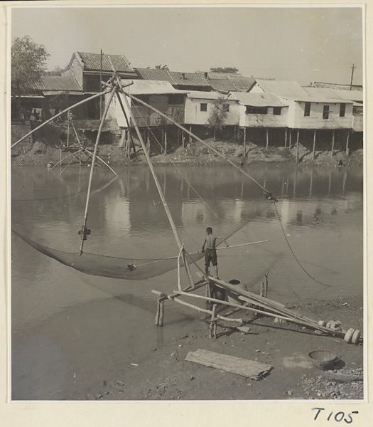 Man removing fish from a large net along the river at Tai'an