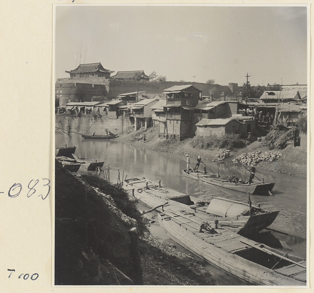 Boats on the river at Tai'an, houses with porches on stilts, and city walls in the background