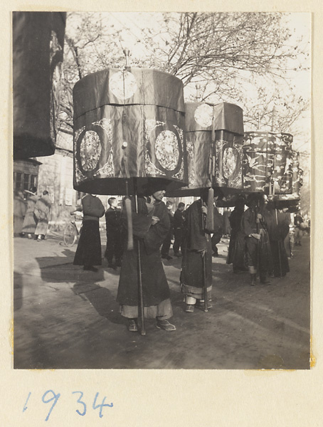 Members of a funeral procession holding umbrellas