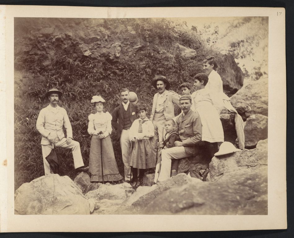 Anna Drew (back row, right) with daughters Lucy and Dora and group of unidentified people posing on large rocks, somewhere near Canton