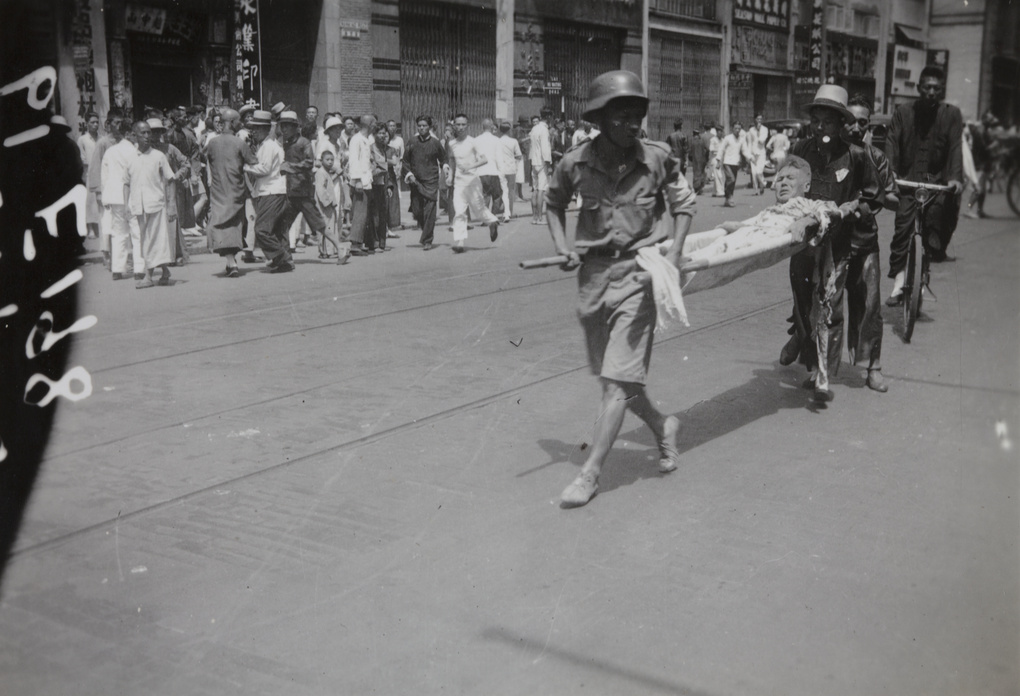An injured man on a stretcher, after the bombing of Sincere Company and Wing On department stores, Shanghai, 23 August 1937