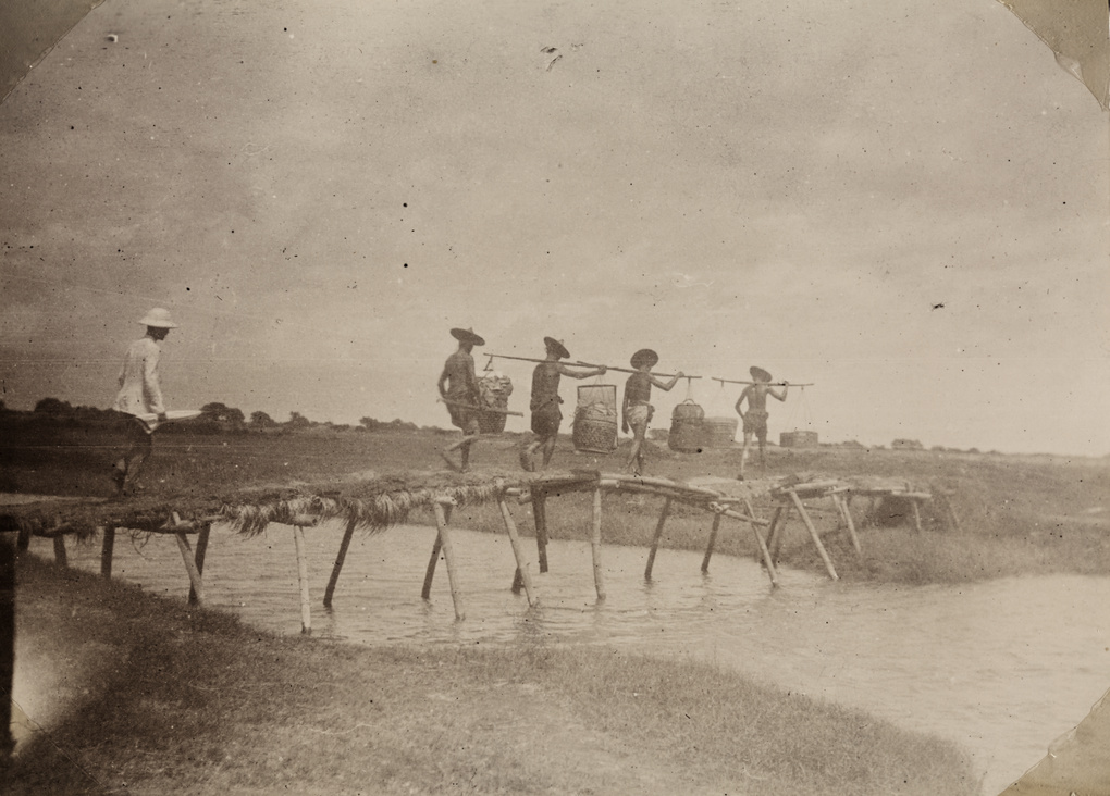 Dr James Laidlaw Maxwell and porters crossing a wooden foot bridge near Donggang, Taiwan