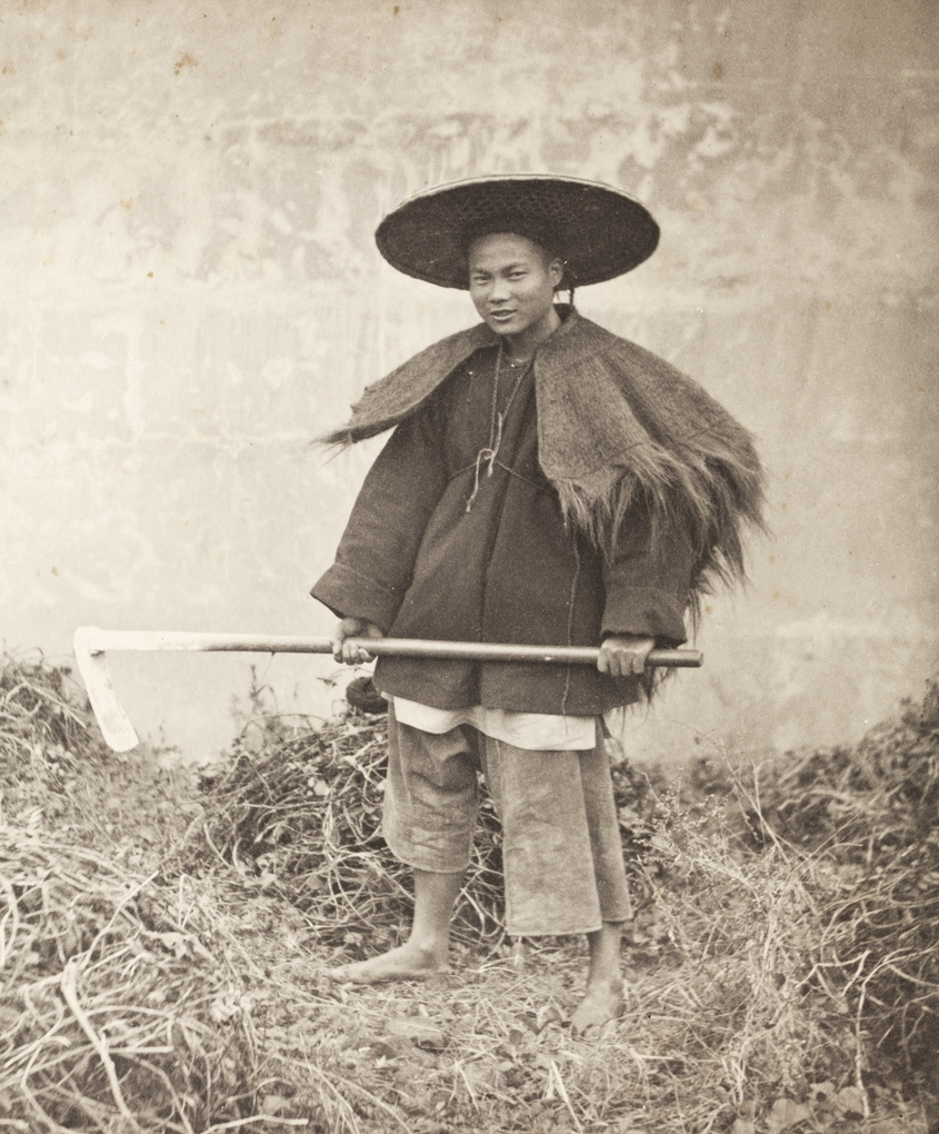 A farm worker with an adze, hat and rain cape