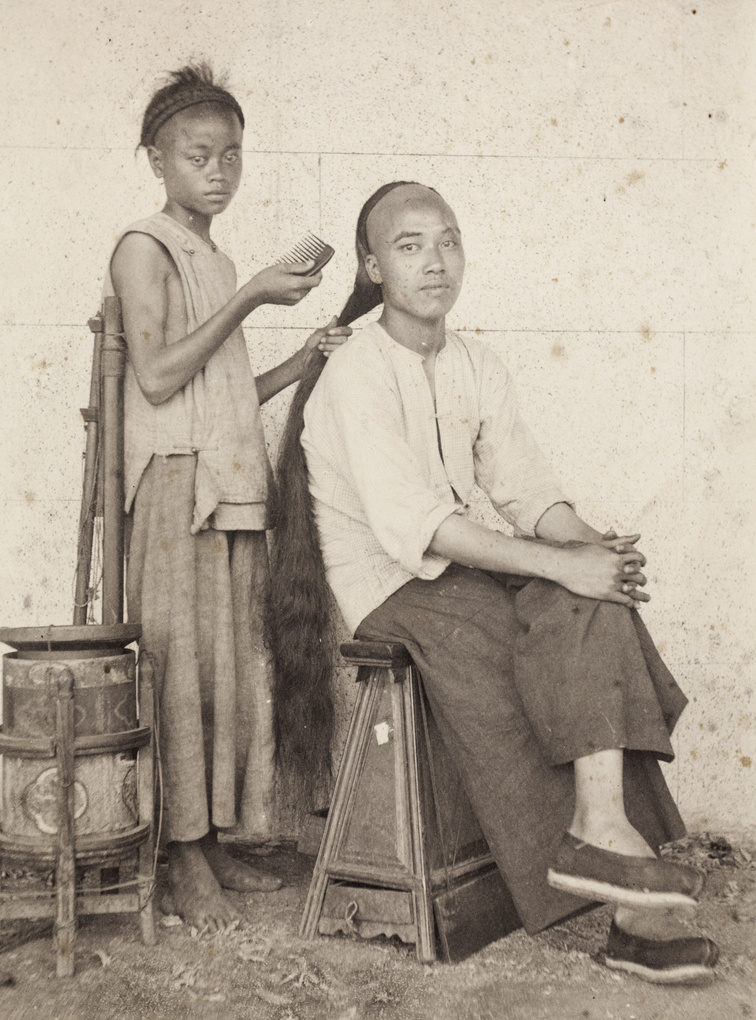 An itinerant barber posed combing the queue of a customer