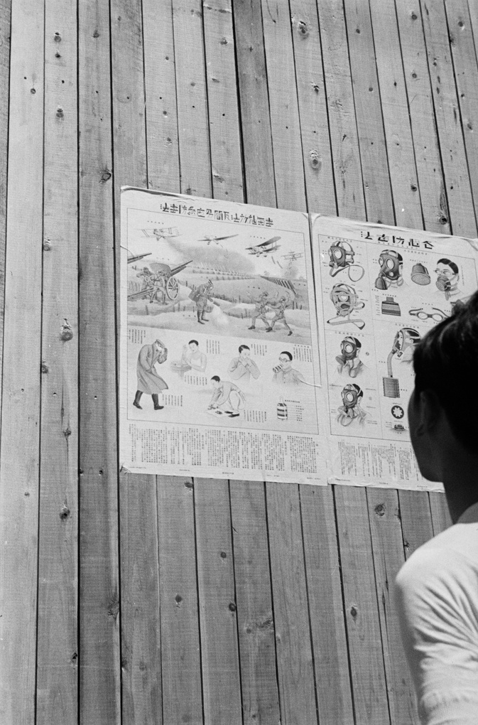 Woman reading aerial attack and gas mask information posters, Shanghai