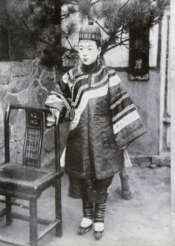 Chinese woman, with bound feet, beside a chair