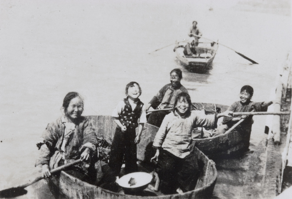 Laughing women and children in round rowing boats