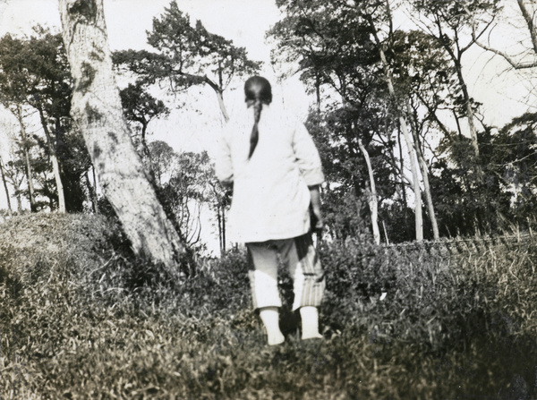 A woman by a field and trees