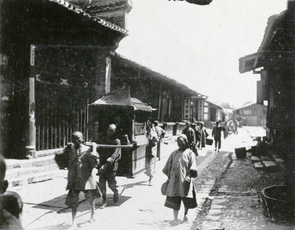 Carrying a sedan chair along a street