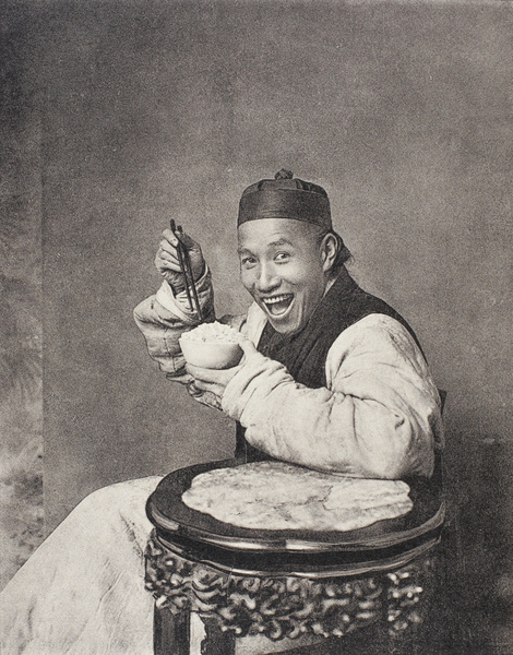 A smiling man posed eating, in a photographer's studio