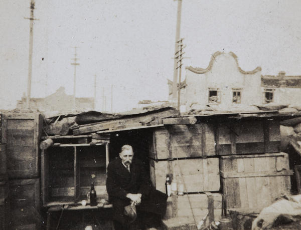A man beside a shelter made from packing crates, Zhabei, Shanghai, 1932