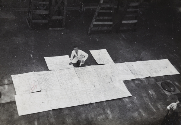 Mr Pulman with a very large map of Shanghai assembled on the printing factory floor, Shanghai