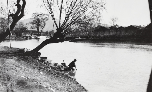 A woman washing laundry on riverbank steps