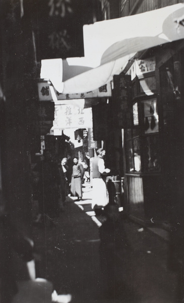 Shadow and light in a narrow street with shops and signs