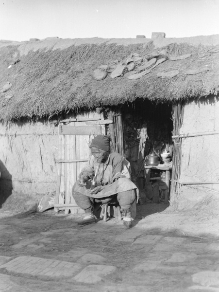 An old woman with bound feet, smoking a pipe, 1920s