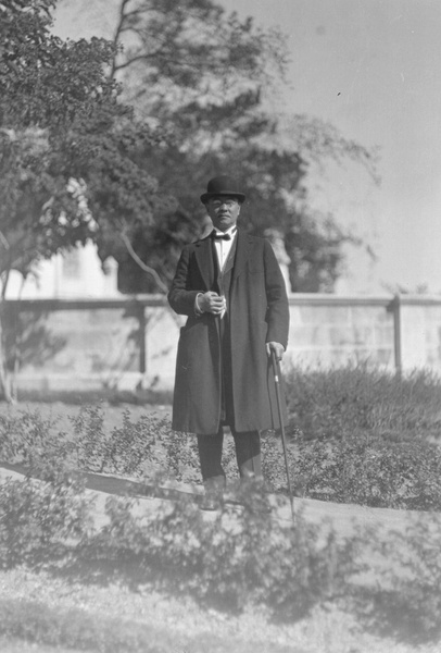 A man wearing hat, overcoat and wing collar shirt