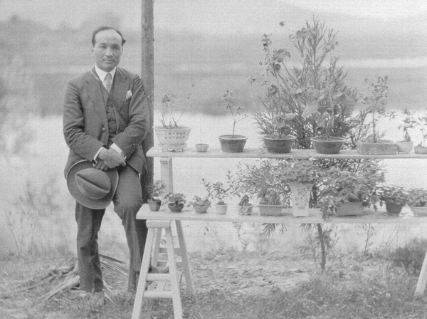 Chu Minyi beside a display of bonsai