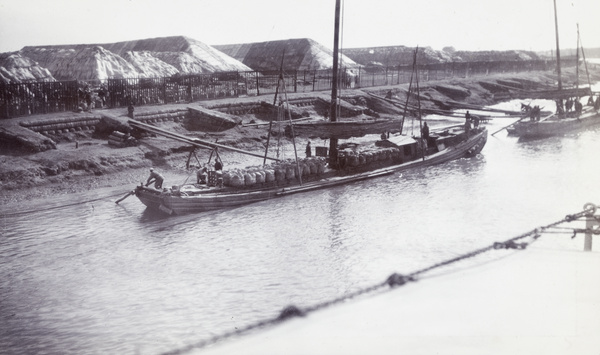 Loading salt onto barges, beside salt stacks, Tianjin