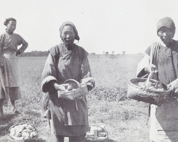 Three women with baskets of produce for sale