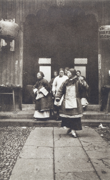 Older women with bound feet stepping into a temple courtyard