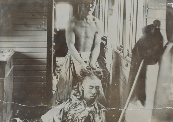 A man holding up a corpse for the camera