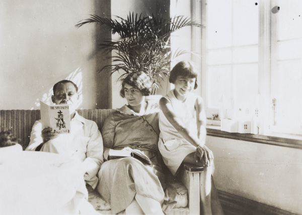Felix Hookham reading ‘The Specialist’ by Charles Sale, beside his wife and daughter, Repulse Bay Hotel, Hong Kong
