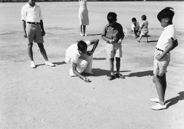 Children playing marbles in a playground in the Prince Edward Road area, Kowloon, Hong Kong