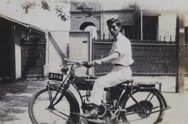 Tom Hutchinson on a motorbike in the street outside 35 Tongshan Road, Hongkou, Shanghai