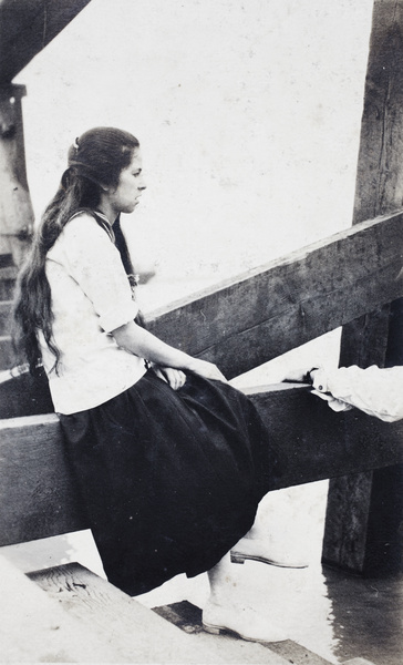 Woman sitting at the base of a wooden water pylon, Shanghai