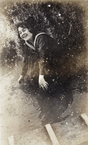 Laughing woman dipping her hand in river water, Shanghai