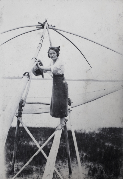 Woman with bare feet standing on a fishing drop-net structure, near Shanghai