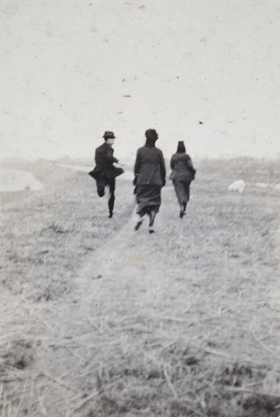 A man and two women running along a path beside a river and away from the photographer, Shanghai