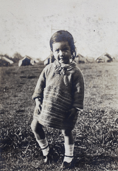 Bea Hutchinson wearing a hand knitted jumper, standing in a park with canvas tents, Shanghai