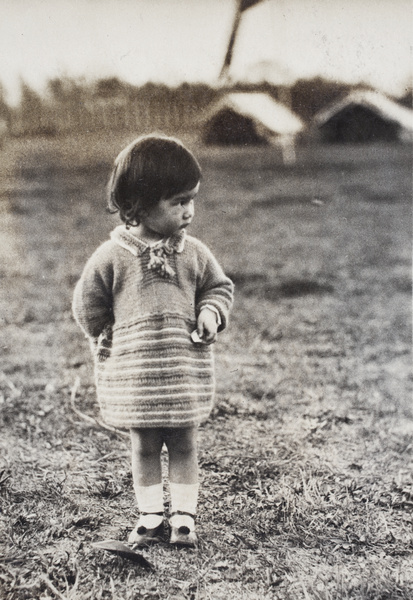 Bea Hutchinson wearing a hand knitted jumper, standing in a park with canvas tents, Shanghai