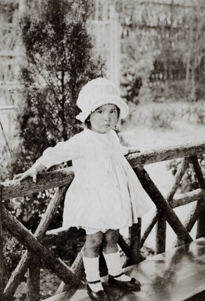 Bea Hutchinson standing on the seat in the garden summer house, 35 Tongshan Road, Hongkou, Shanghai