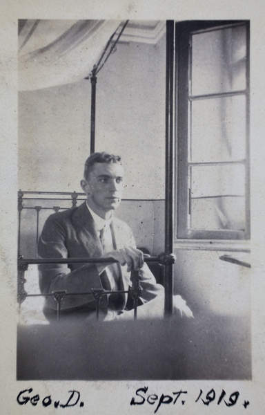 George Danson sitting on an iron-frame bed, 35 Tongshan Road, Hongkou, Shanghai