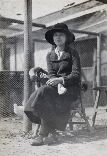 Sarah Hutchinson sitting outside a chicken enclosure, holding two eggs in one hand, Hongkou, Shanghai