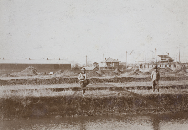 Man casting a fishing net over a waterway by a field with grave mounds