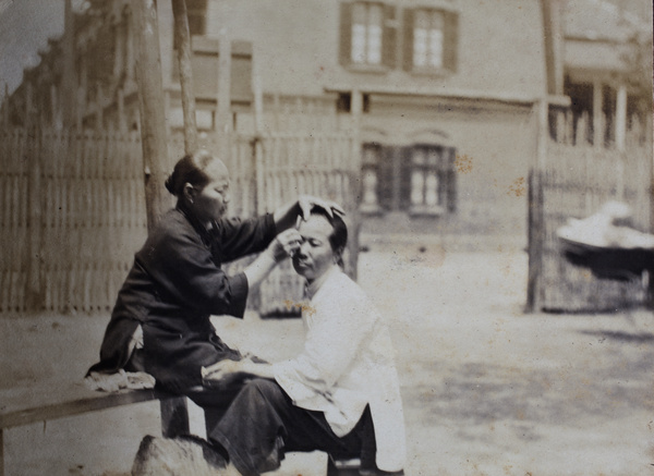 Woman dressing the hair of an amah in the street, Shanghai 